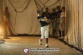 Baseball player swinging at a pitch inside a netted pitching dome