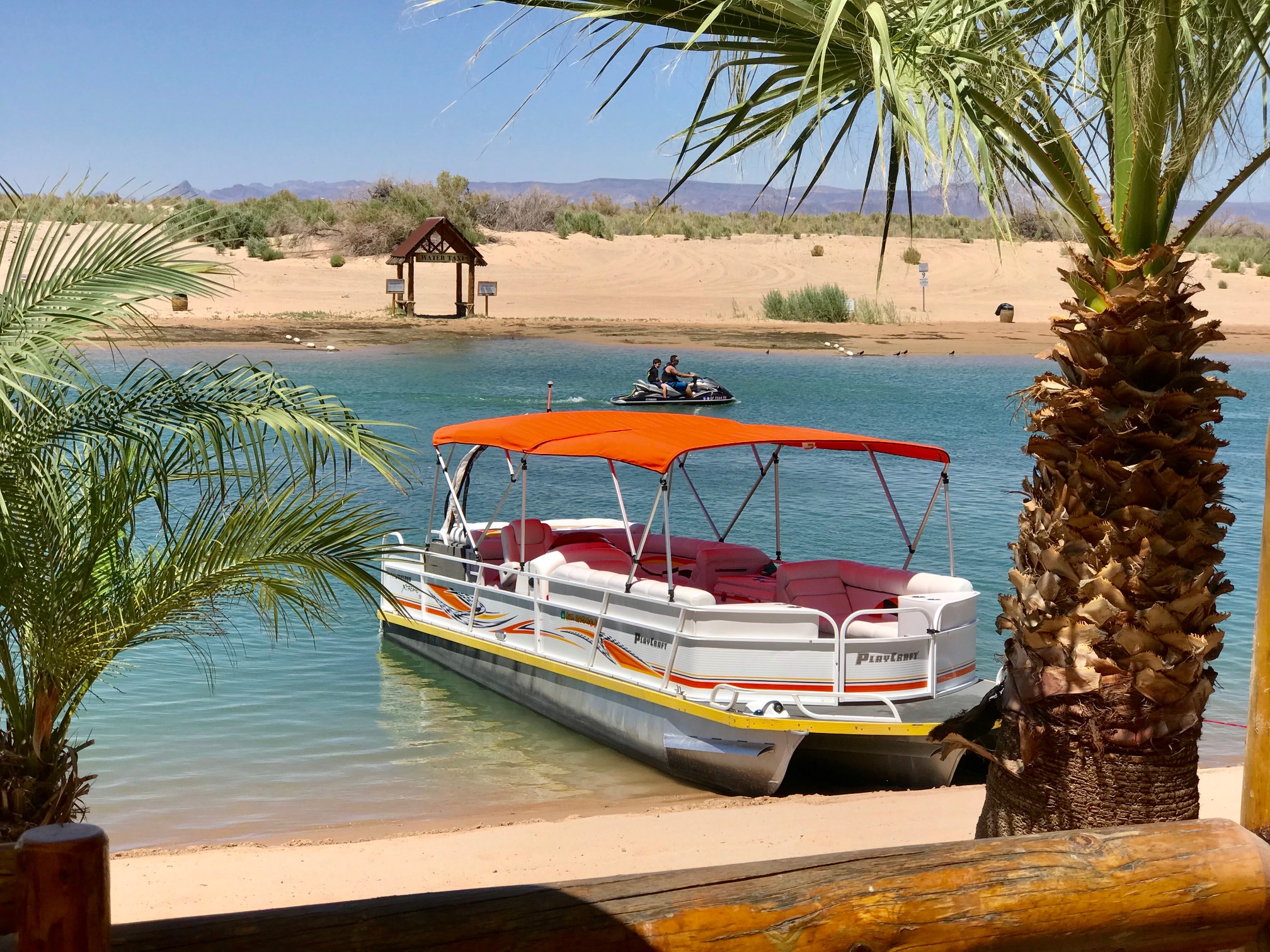 Orange dual pontoon bimini top installed on a Playcraft Powertoon