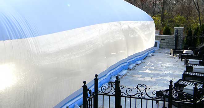 Blue water-tube ballast around the outside of a pool dome on a stone patio